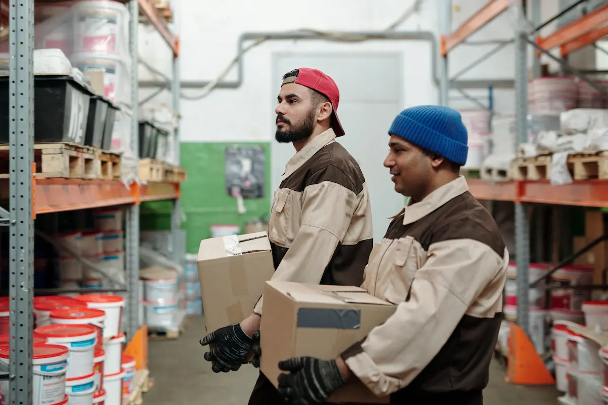 Deux agents logistiques transportant des cartons dans un entrepôt