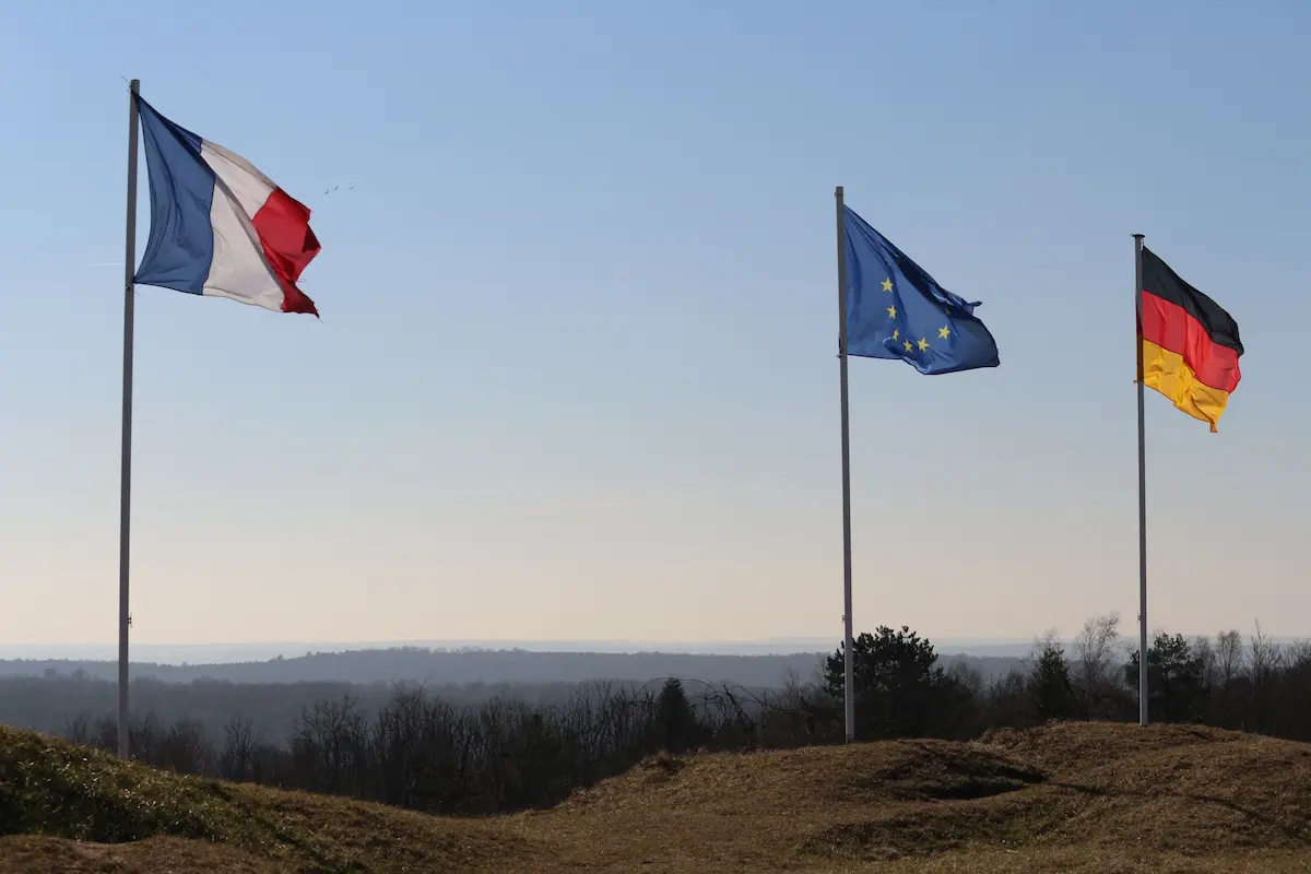 Drapeaux de la France, de l'Union européenne et de l'Allemagne flottant sur une colline, sous un ciel bleu