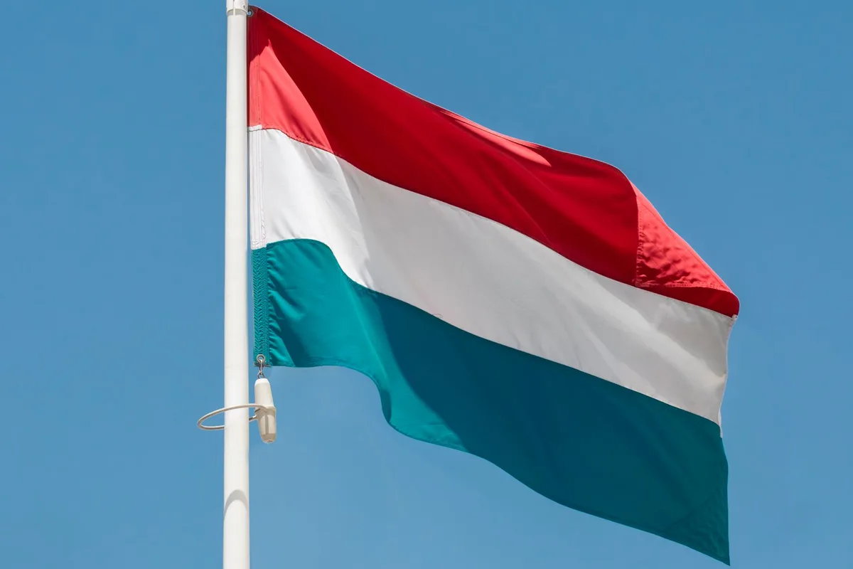 Drapeau luxembourgeois rouge, blanc et bleu clair flottant sous un ciel bleu